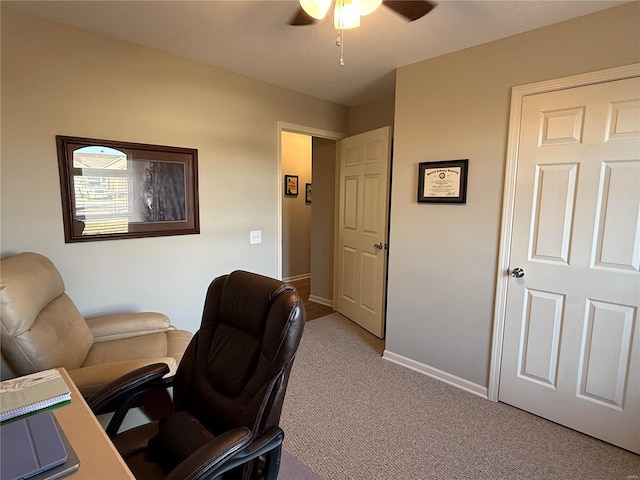 office space featuring baseboards, a ceiling fan, and light colored carpet