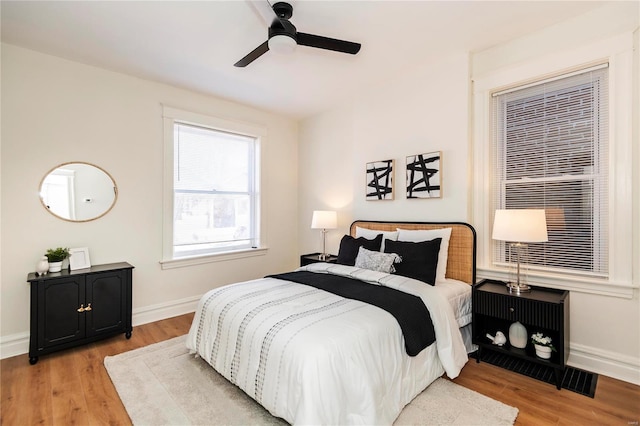 bedroom with light wood finished floors, a ceiling fan, and baseboards