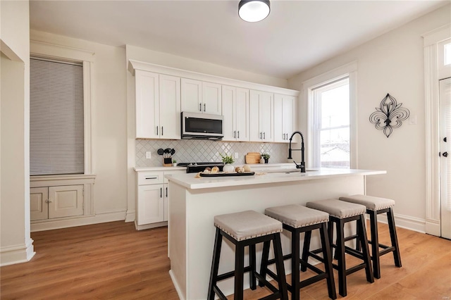 kitchen featuring tasteful backsplash, stainless steel microwave, a kitchen bar, and a sink