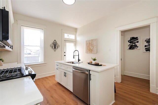 kitchen featuring a center island with sink, a sink, white cabinets, light wood finished floors, and dishwasher