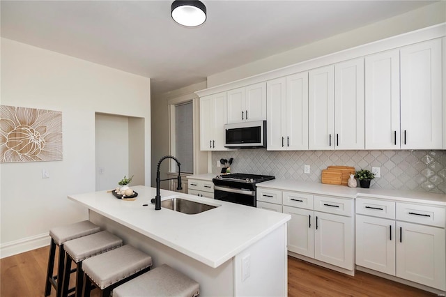 kitchen featuring a sink, range with gas cooktop, tasteful backsplash, and a breakfast bar