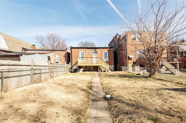 rear view of property featuring brick siding, central AC, and a fenced backyard