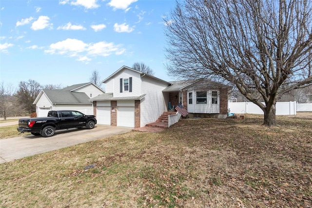 tri-level home with brick siding, concrete driveway, an attached garage, a front yard, and fence