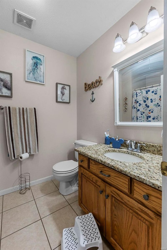 bathroom featuring toilet, vanity, baseboards, visible vents, and tile patterned floors