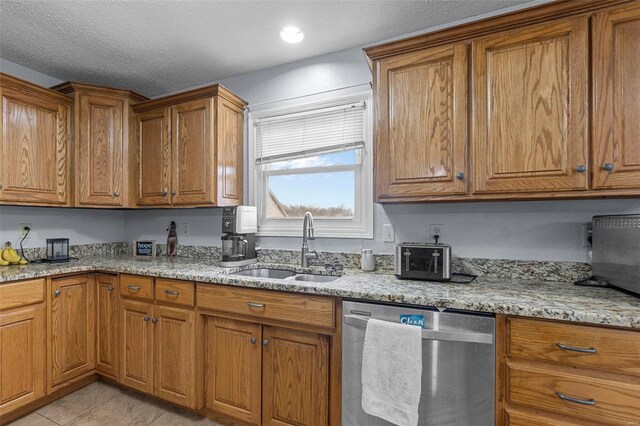 kitchen with stainless steel dishwasher, brown cabinetry, light tile patterned flooring, and a sink