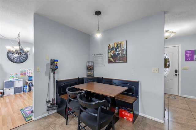 tiled dining room with an inviting chandelier, baseboards, and a textured ceiling