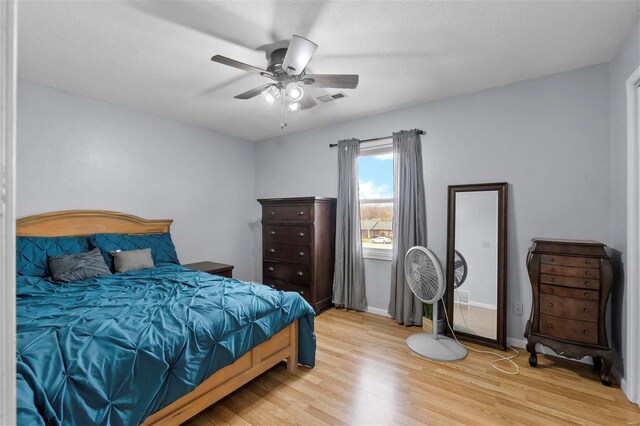 bedroom featuring light wood-type flooring, baseboards, visible vents, and a ceiling fan