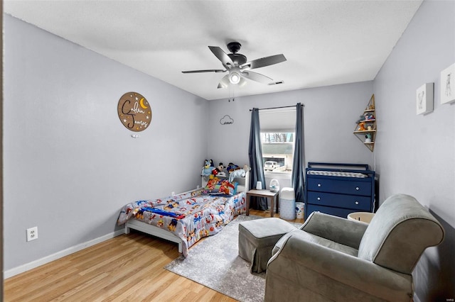 bedroom featuring a ceiling fan, visible vents, baseboards, and wood finished floors