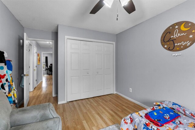 bedroom with light wood finished floors, a closet, a ceiling fan, and baseboards