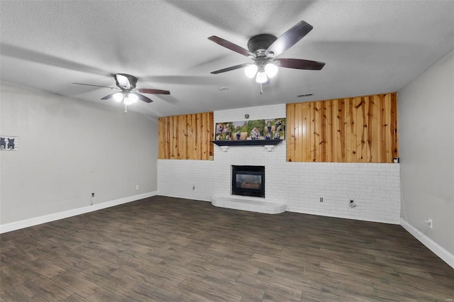 unfurnished living room with a textured ceiling, brick wall, dark wood-type flooring, and a fireplace