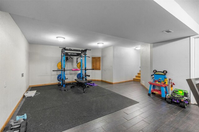 exercise room with wood finished floors, visible vents, and baseboards