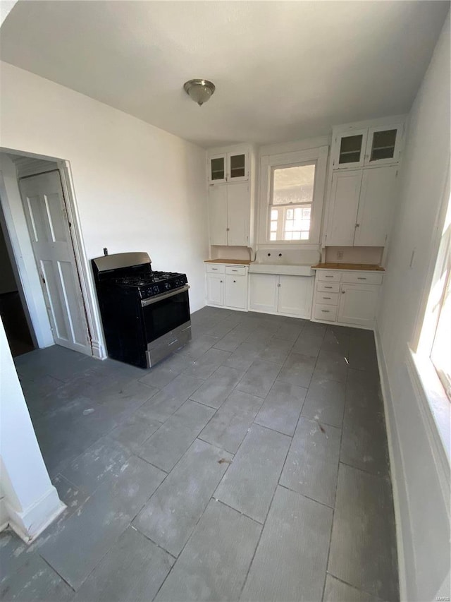 kitchen with stainless steel gas stove, glass insert cabinets, and white cabinetry