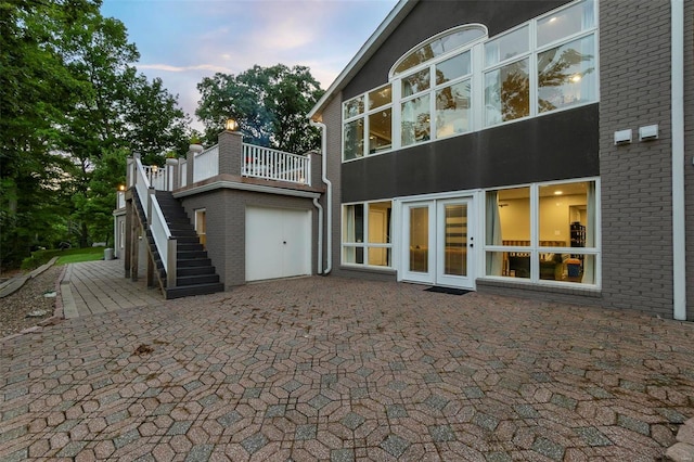 back of property at dusk with brick siding, stairs, and a patio