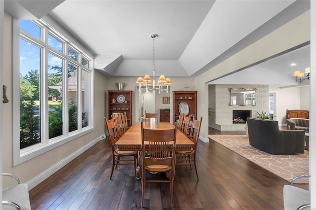 dining area featuring a chandelier, dark wood-type flooring, a fireplace, and baseboards