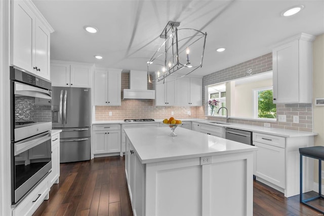 kitchen featuring wall chimney exhaust hood, appliances with stainless steel finishes, white cabinets, and a sink