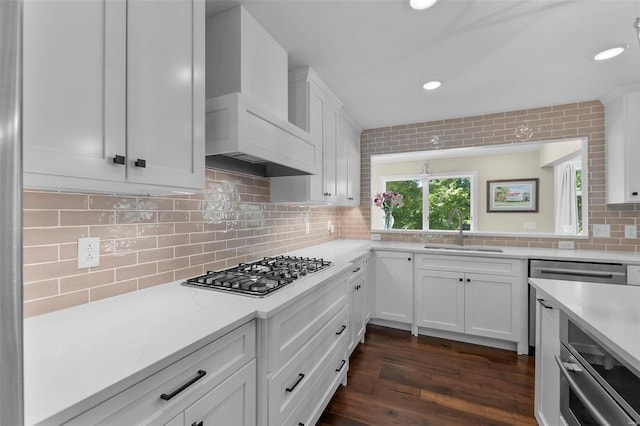 kitchen with stainless steel gas cooktop, custom exhaust hood, light countertops, decorative backsplash, and a sink