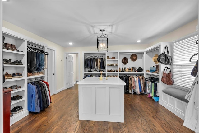 walk in closet with dark wood-style flooring and a notable chandelier