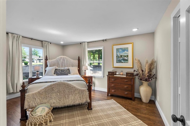 bedroom with dark wood-style flooring, multiple windows, and baseboards