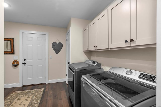 clothes washing area with dark wood-style floors, washing machine and dryer, cabinet space, and baseboards