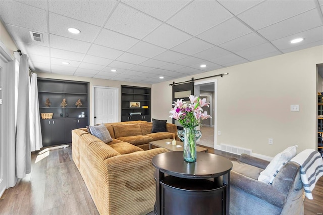 living area with a barn door, visible vents, wood finished floors, and recessed lighting