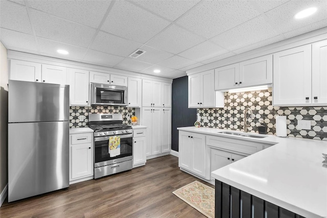 kitchen with white cabinets, dark wood finished floors, stainless steel appliances, light countertops, and a sink