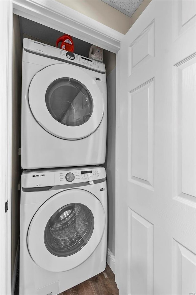 washroom featuring stacked washer and dryer, laundry area, and dark wood-style flooring