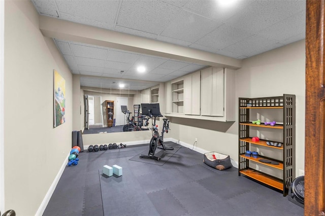 workout room with a drop ceiling and baseboards