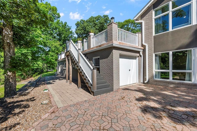 rear view of property with a garage, a patio area, stairway, and brick siding