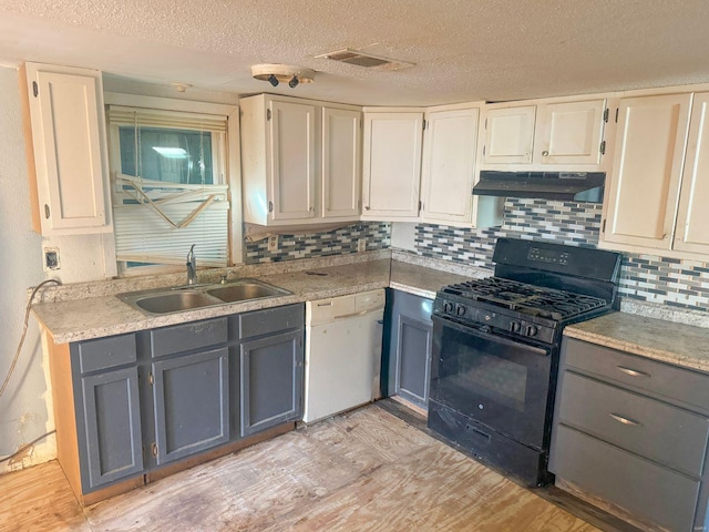 kitchen featuring white dishwasher, under cabinet range hood, a sink, visible vents, and black gas stove