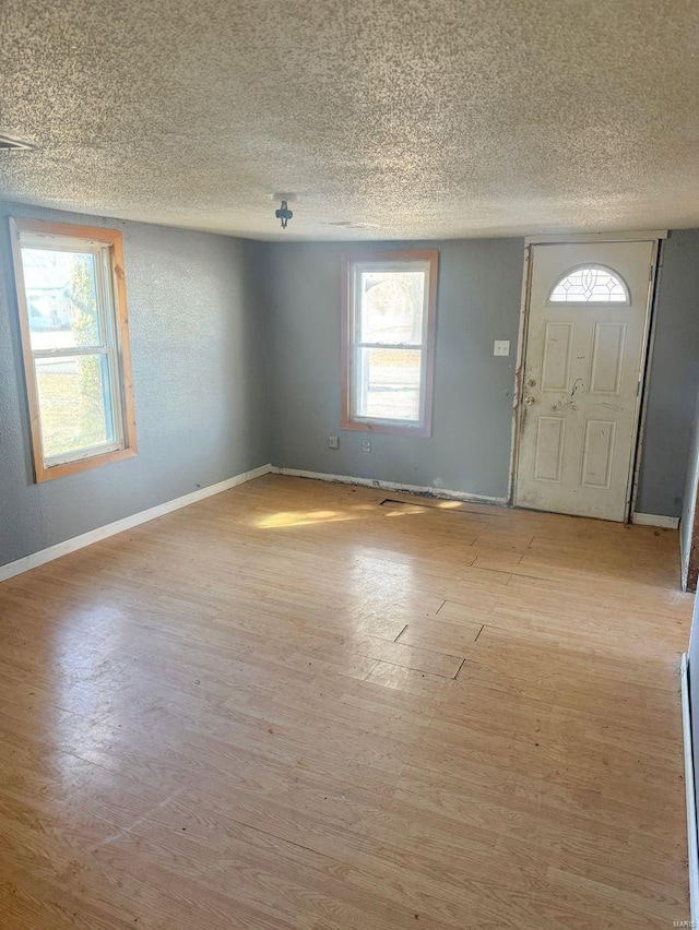 entrance foyer with light wood-style floors, baseboards, and a textured ceiling