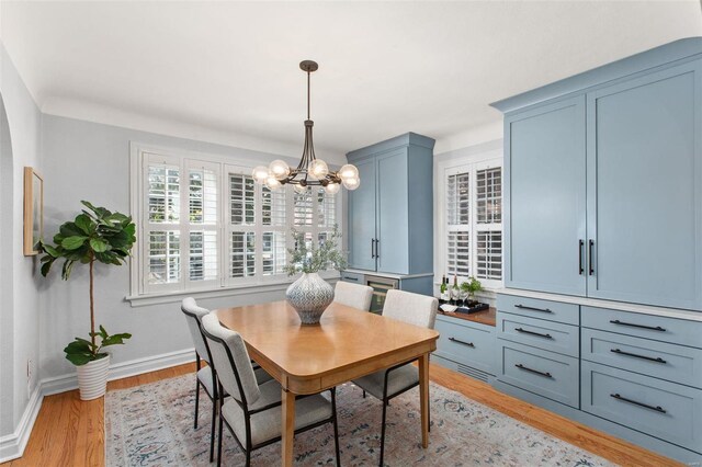 dining room featuring light wood-style flooring, an inviting chandelier, and baseboards