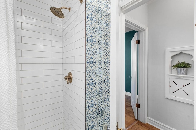 bathroom with wood finished floors, baseboards, and a stall shower