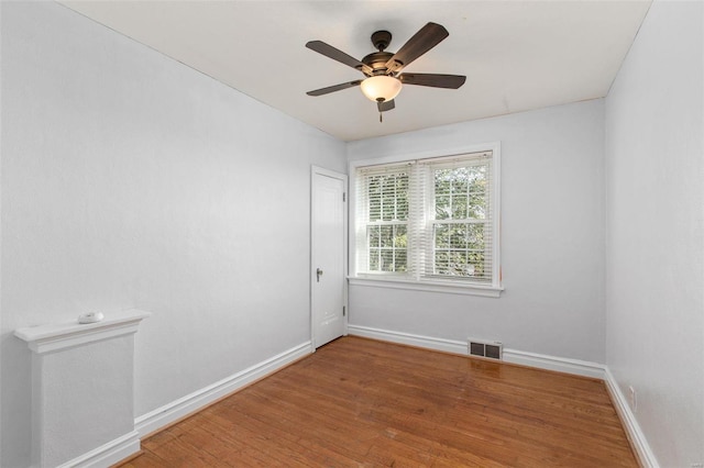 unfurnished room featuring a ceiling fan, wood finished floors, visible vents, and baseboards