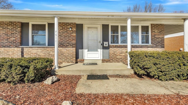 entrance to property featuring covered porch and brick siding