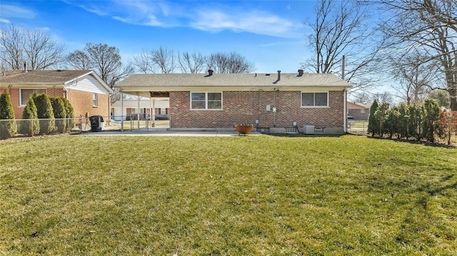 back of property with a carport, brick siding, and a lawn