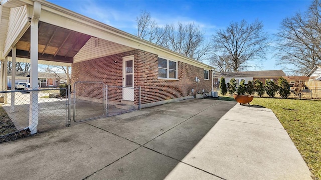 view of home's exterior with central air condition unit, brick siding, fence, a yard, and a gate