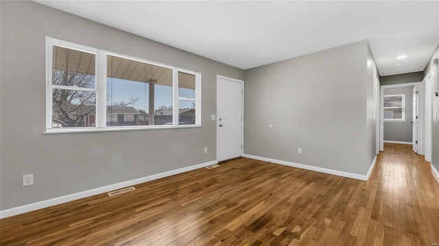 unfurnished room with baseboards, visible vents, and hardwood / wood-style floors