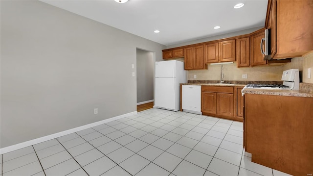 kitchen featuring recessed lighting, white appliances, a sink, baseboards, and brown cabinets