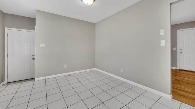 unfurnished room featuring light tile patterned floors, visible vents, and baseboards