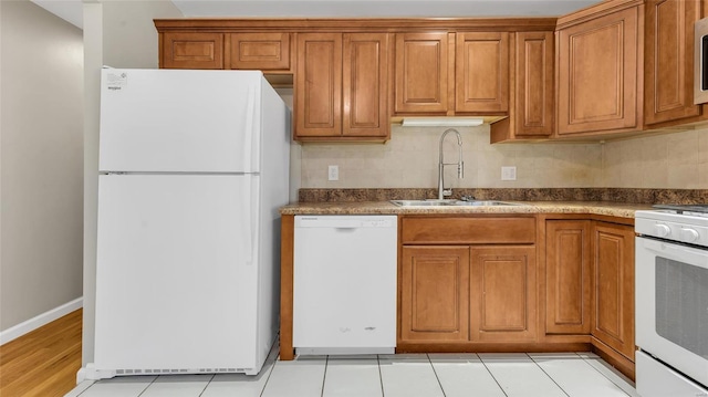 kitchen with tasteful backsplash, white appliances, brown cabinets, and a sink