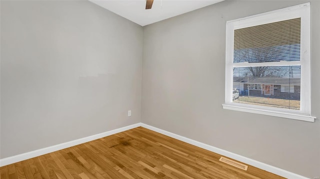 spare room with ceiling fan, wood finished floors, visible vents, and baseboards