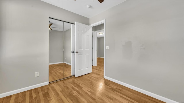 unfurnished bedroom featuring ceiling fan, a closet, wood finished floors, and baseboards