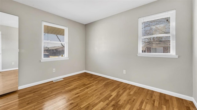 spare room featuring plenty of natural light, visible vents, and wood finished floors