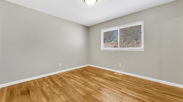 unfurnished room featuring light wood-type flooring, visible vents, and baseboards