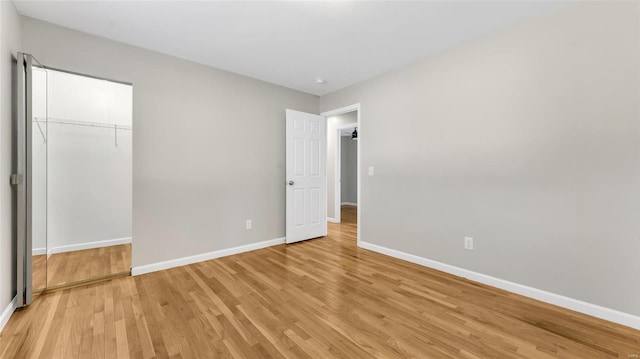 unfurnished bedroom featuring light wood-style floors, baseboards, and a closet