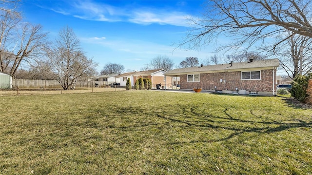 rear view of house with a yard, a patio area, fence, and brick siding