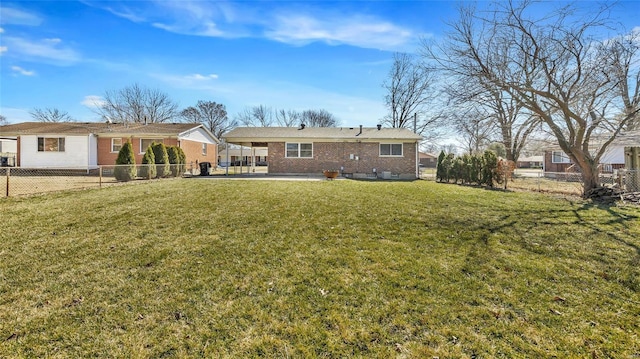 rear view of house featuring an attached carport, a fenced backyard, and a lawn