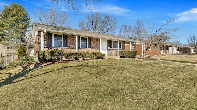 ranch-style home featuring brick siding, fence, and a front lawn