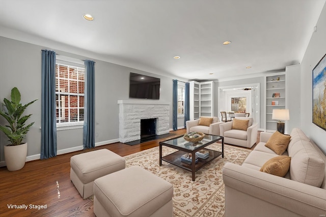 living area featuring baseboards, a fireplace, wood finished floors, and recessed lighting