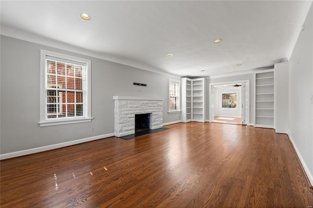 unfurnished living room featuring a fireplace, wood finished floors, and baseboards